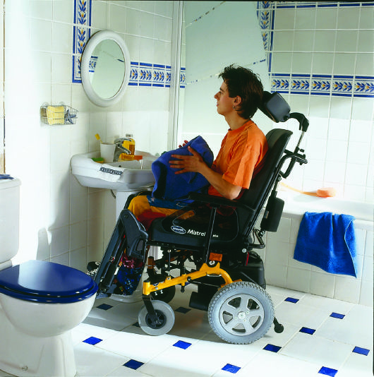 A disabled person in use of mobility aids for bathroom